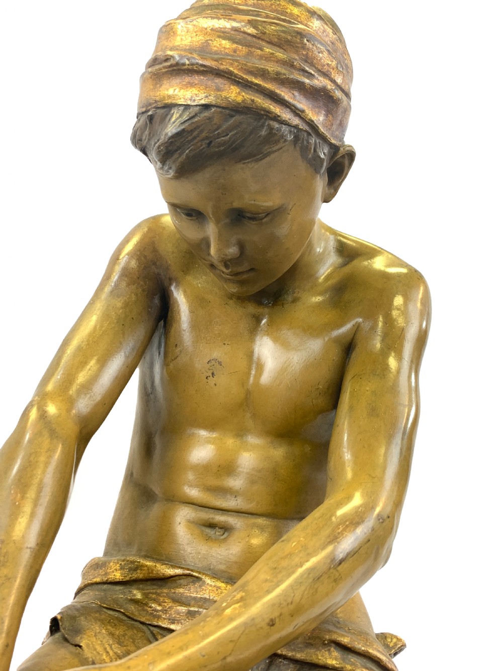 A late 19th-century Goldscheider cold-painted terracotta figure depicting a seated boy with a headscarf on a rocky base, finished in a bronzed metallic glaze. View V