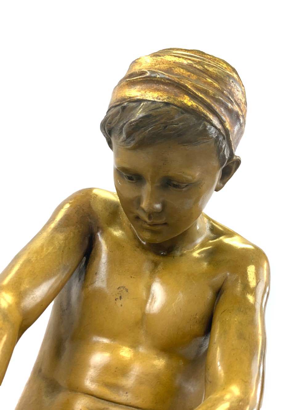 A late 19th-century Goldscheider cold-painted terracotta figure depicting a seated boy with a headscarf on a rocky base, finished in a bronzed metallic glaze. View VII