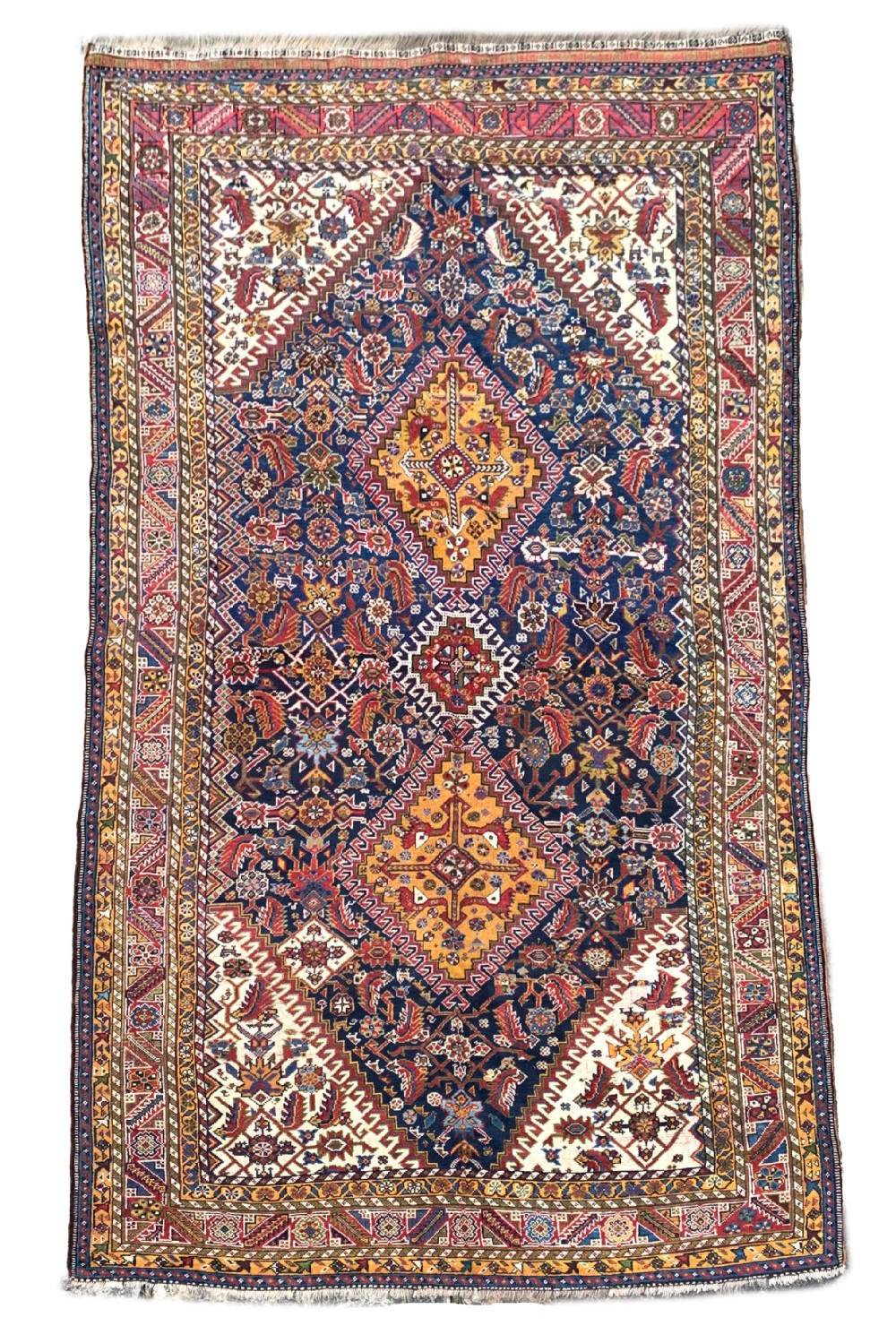 An antique Persian Qashqai hand-knotted wool rug featuring geometric diamond medallions on a navy blue tribal field with intricate multi-tiered borders.