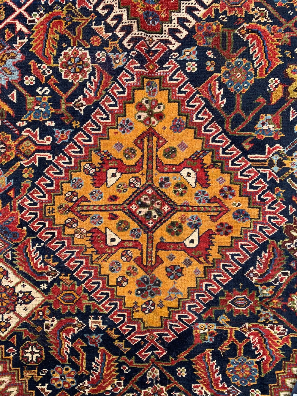 An antique Persian Qashqai hand-knotted wool rug featuring geometric diamond medallions on a navy blue tribal field with intricate multi-tiered borders. View II