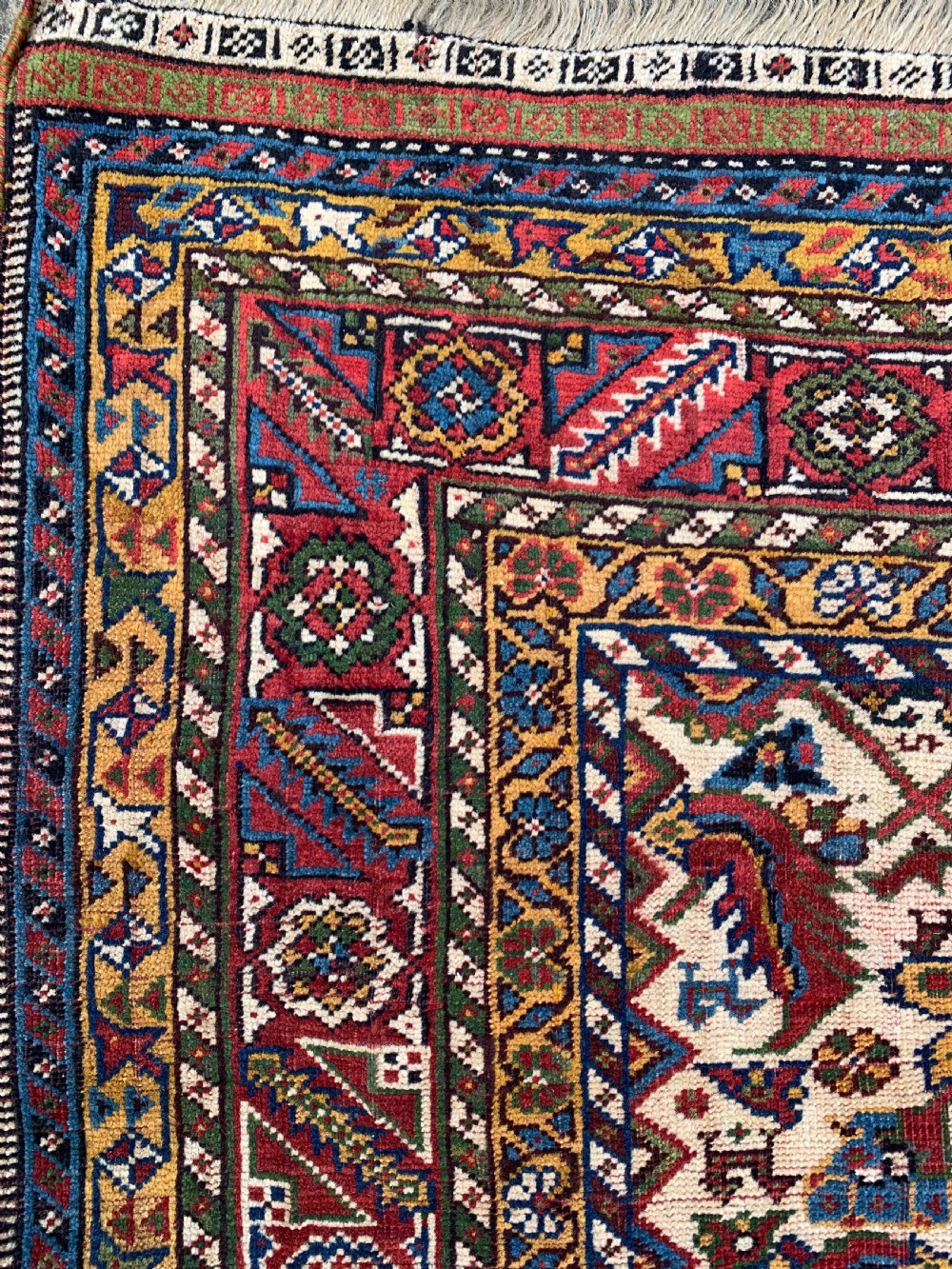 An antique Persian Qashqai hand-knotted wool rug featuring geometric diamond medallions on a navy blue tribal field with intricate multi-tiered borders. View IV
