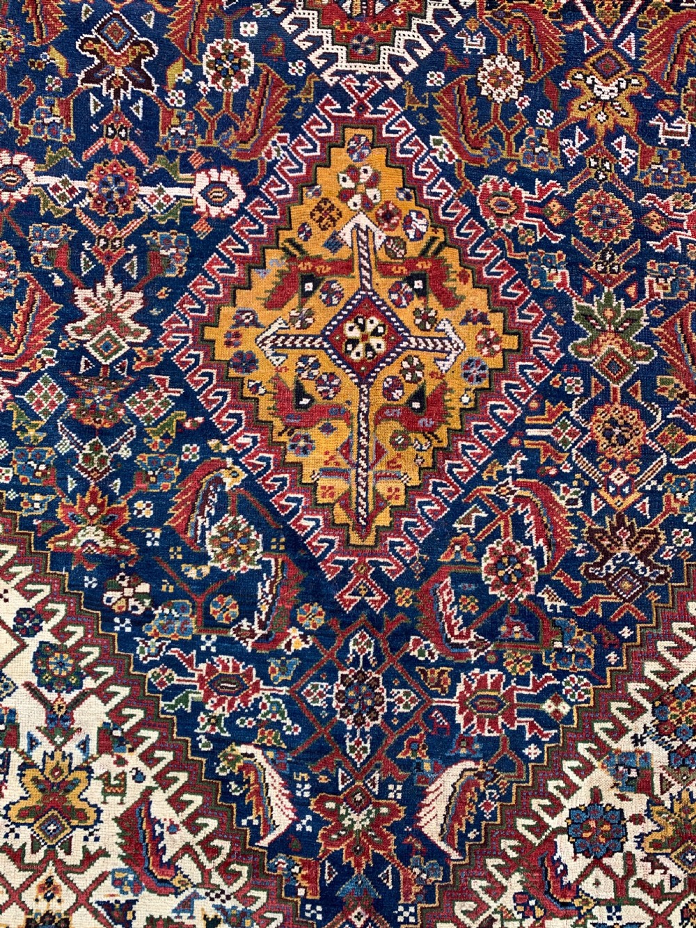 An antique Persian Qashqai hand-knotted wool rug featuring geometric diamond medallions on a navy blue tribal field with intricate multi-tiered borders. View VI