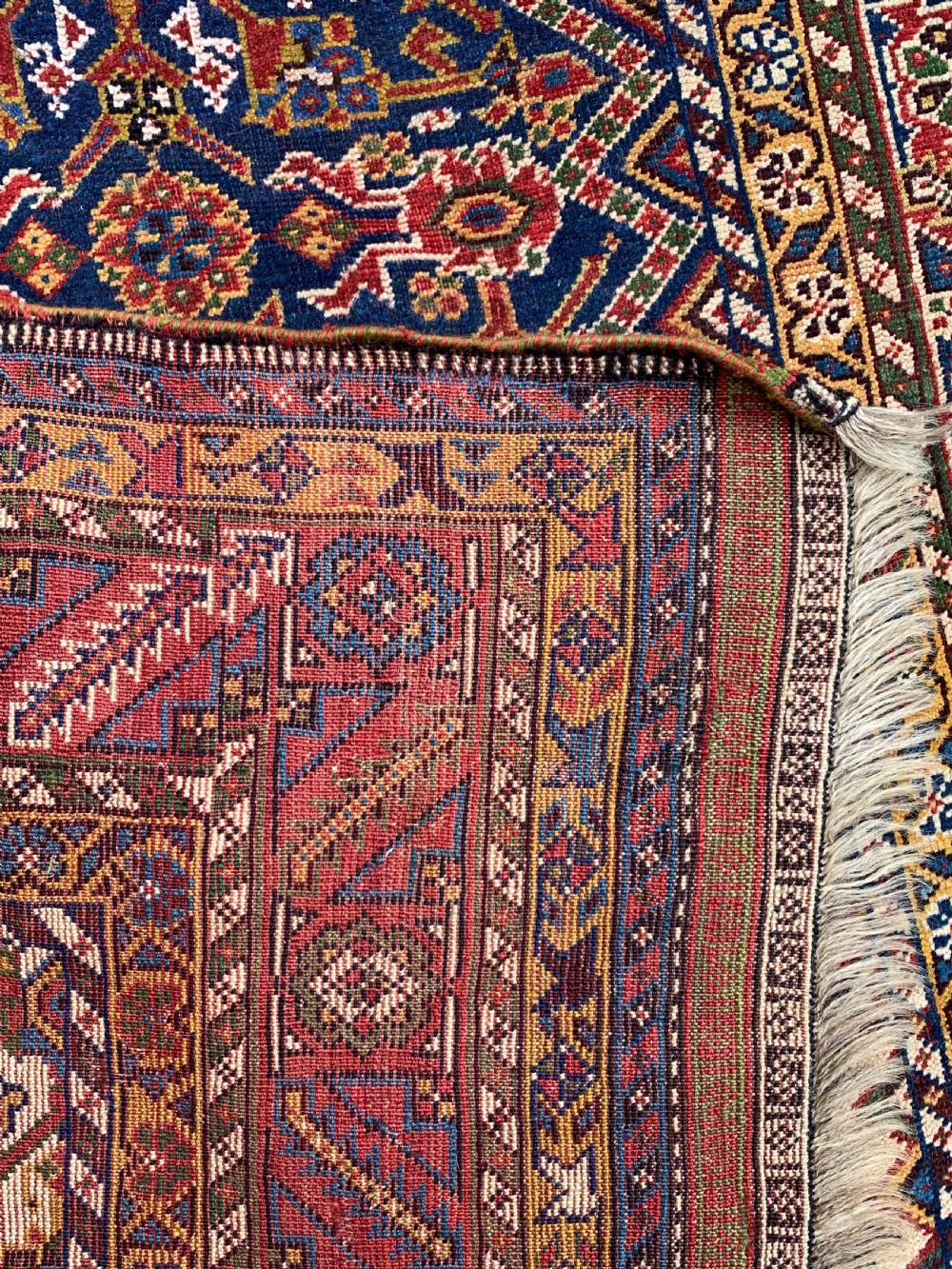 An antique Persian Qashqai hand-knotted wool rug featuring geometric diamond medallions on a navy blue tribal field with intricate multi-tiered borders. View IX