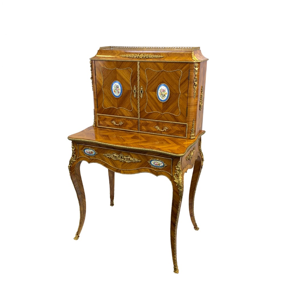 A late 19th-century French kingwood bonheur du jour featuring parquetry veneers, gilt-bronze mounts, oval porcelain plaques, and curved cabriole legs.