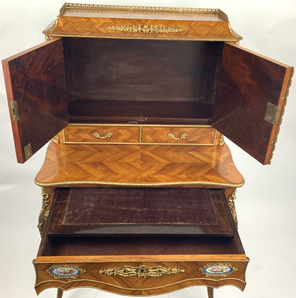 A late 19th-century French kingwood bonheur du jour featuring parquetry veneers, gilt-bronze mounts, oval porcelain plaques, and curved cabriole legs. View IX