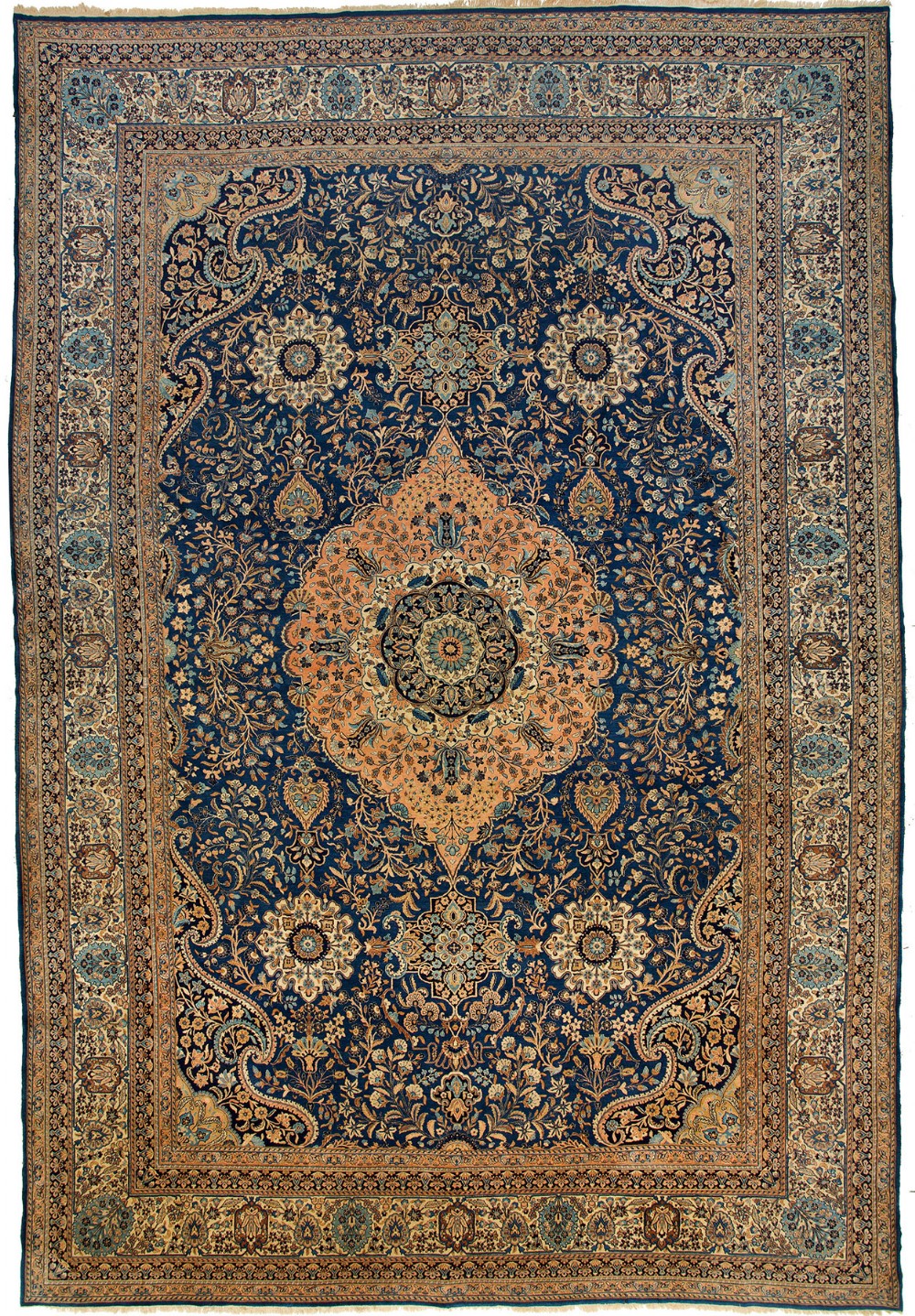 An oversized rectangular Persian Kerman carpet featuring an intricate navy blue field filled with floral arabesques, a central peach medallion, and multiple ornamental borders.