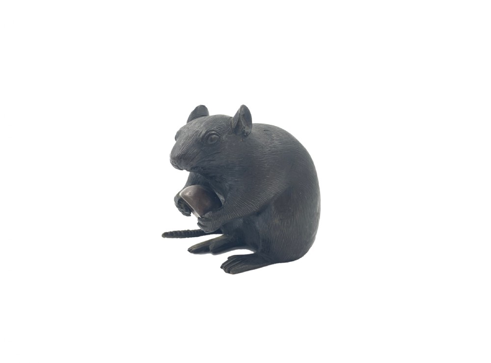 A dark bronze Japanese okimono sculpture depicting a rat sitting upright and clutching a chestnut.