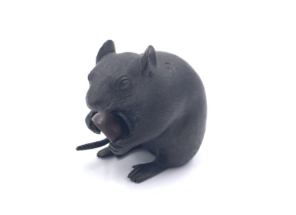 A dark bronze Japanese okimono sculpture depicting a rat sitting upright and clutching a chestnut. View II