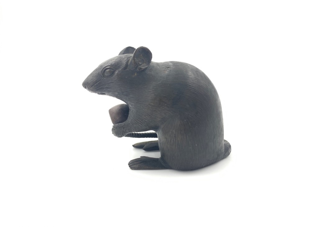 A dark bronze Japanese okimono sculpture depicting a rat sitting upright and clutching a chestnut. View V