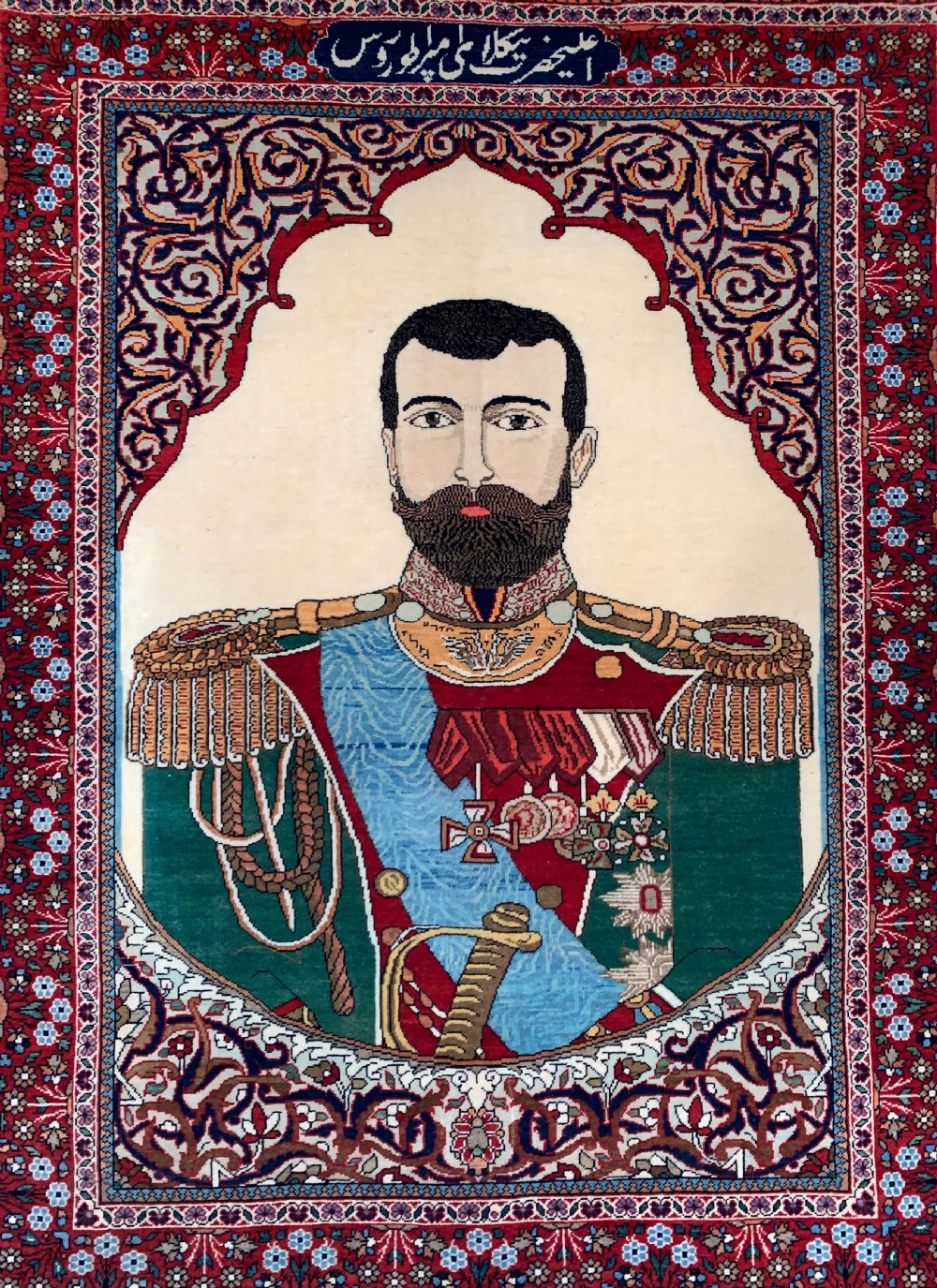 A hand-knotted antique Persian pictorial rug depicting Tsar Nicholas II of Russia in military uniform, framed by a cream archway and a dark red floral border with Persian script. View III
