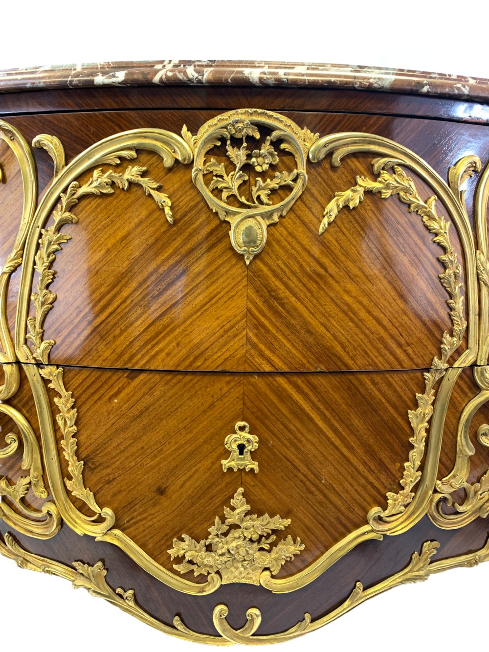 A French Louis XV style bombe commode featuring rich kingwood parquetry veneers, ornate gilt-bronze ormolu mounts, cabriole legs, and a shaped variegated marble top. View III