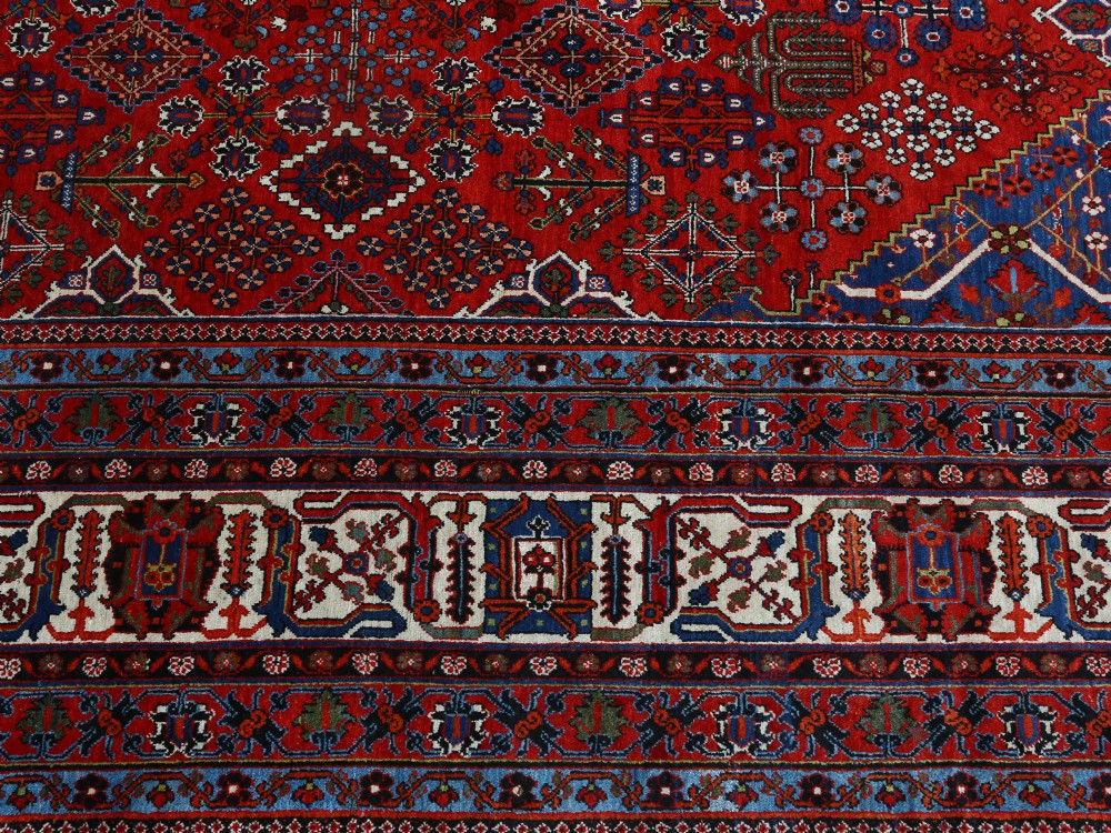A large hand-knotted Persian Joshagan carpet featuring a central diamond medallion, intricate red geometric field, navy spandrels, and decorative borders. View III