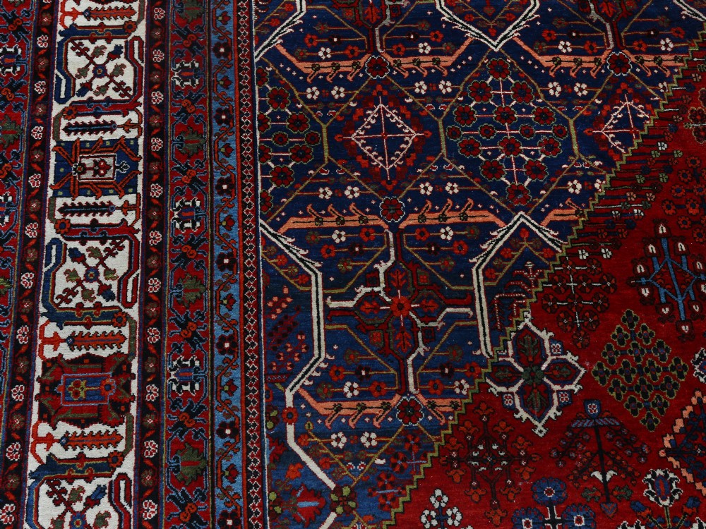 A large hand-knotted Persian Joshagan carpet featuring a central diamond medallion, intricate red geometric field, navy spandrels, and decorative borders. View IV