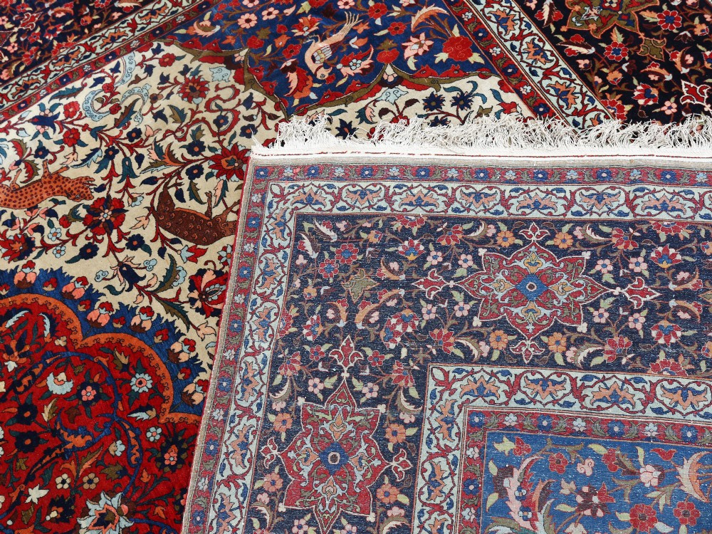 An antique Persian Isfahan wool carpet featuring a central red and blue medallion on an ivory field surrounded by detailed floral and animal patterns with a dark blue border. View IX