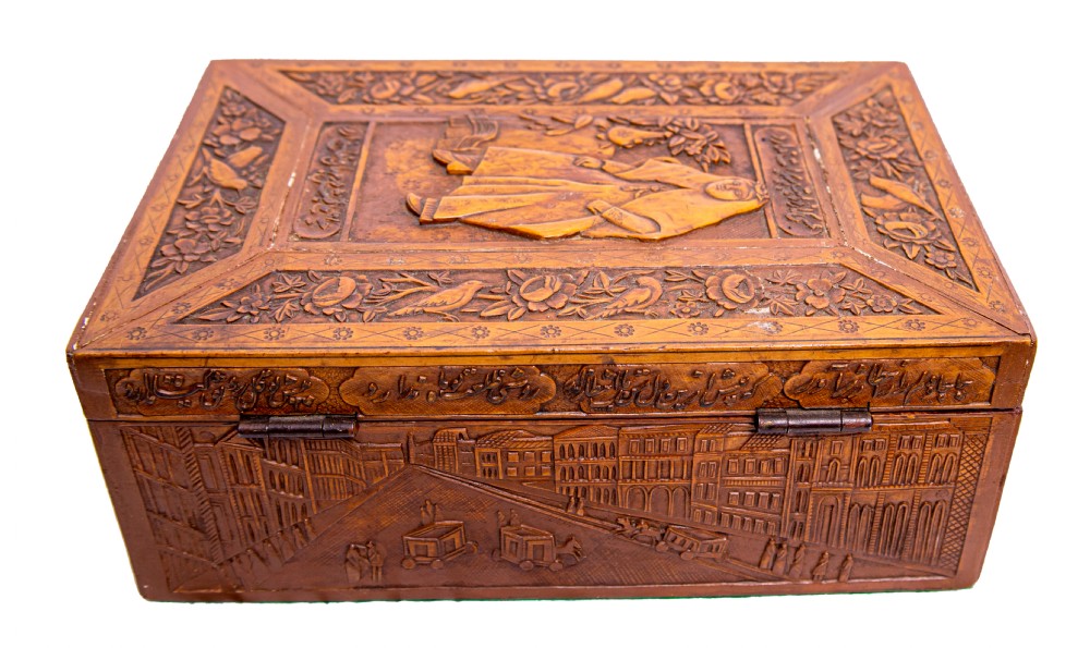 A 19th-century rectangular Qajar Iranian carved wooden casket featuring relief depictions of architectural buildings, figures, and Persian calligraphy. View III