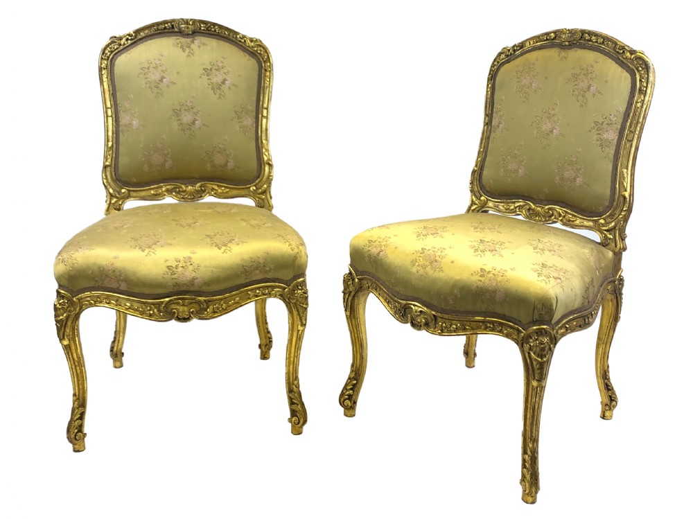 A pair of late 19th-century Rococo Revival giltwood side chairs upholstered in patterned green silk fabric with carved cabriole legs.