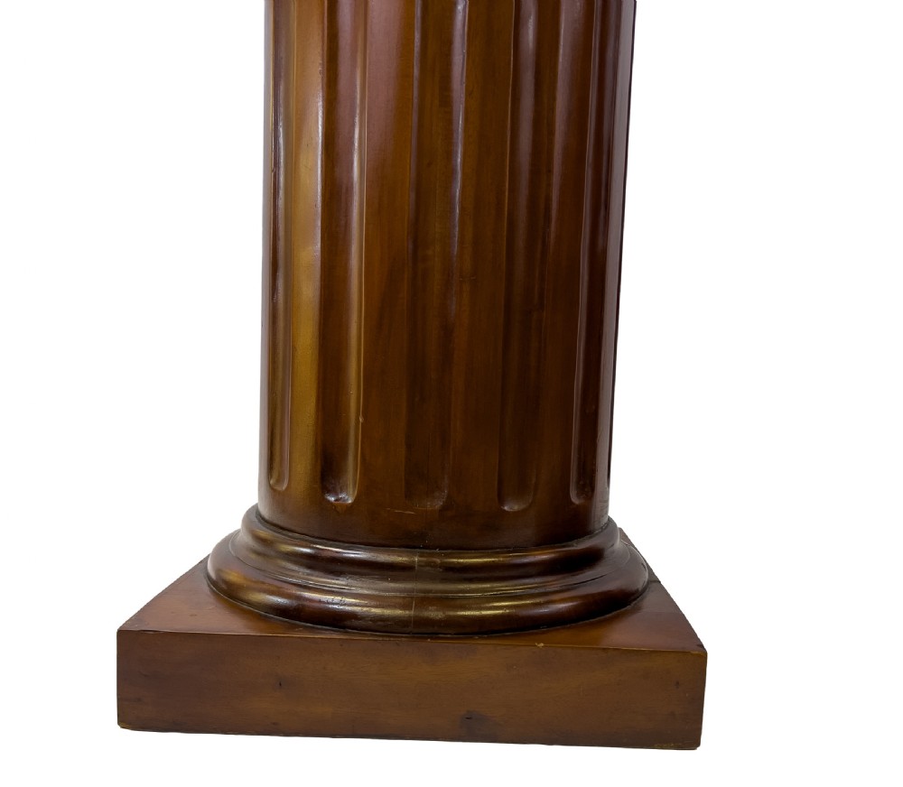 A pair of carved warm brown wooden pedestals styled as classical Ionic columns with fluted shafts and square bases. View V