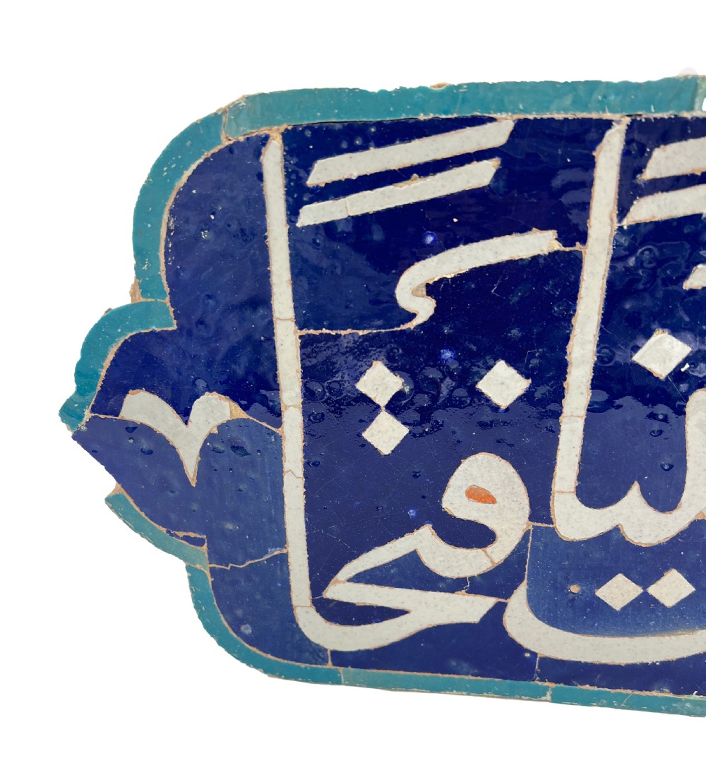 An elongated cobalt blue ceramic tile featuring white Arabic calligraphic script framed within a turquoise border. View V