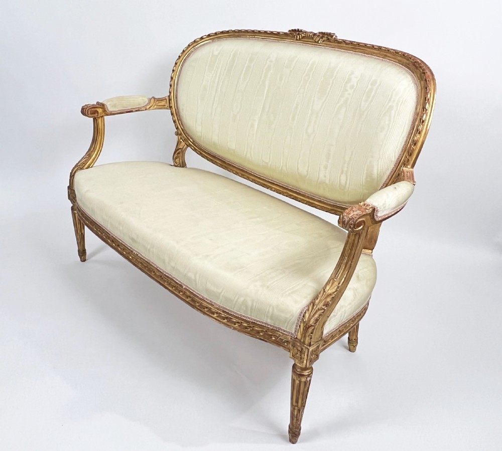 A five-piece 19th-century French Louis XVI style giltwood salon suite featuring a three-seater settee and four matching fauteuil armchairs upholstered in cream fabric. View III