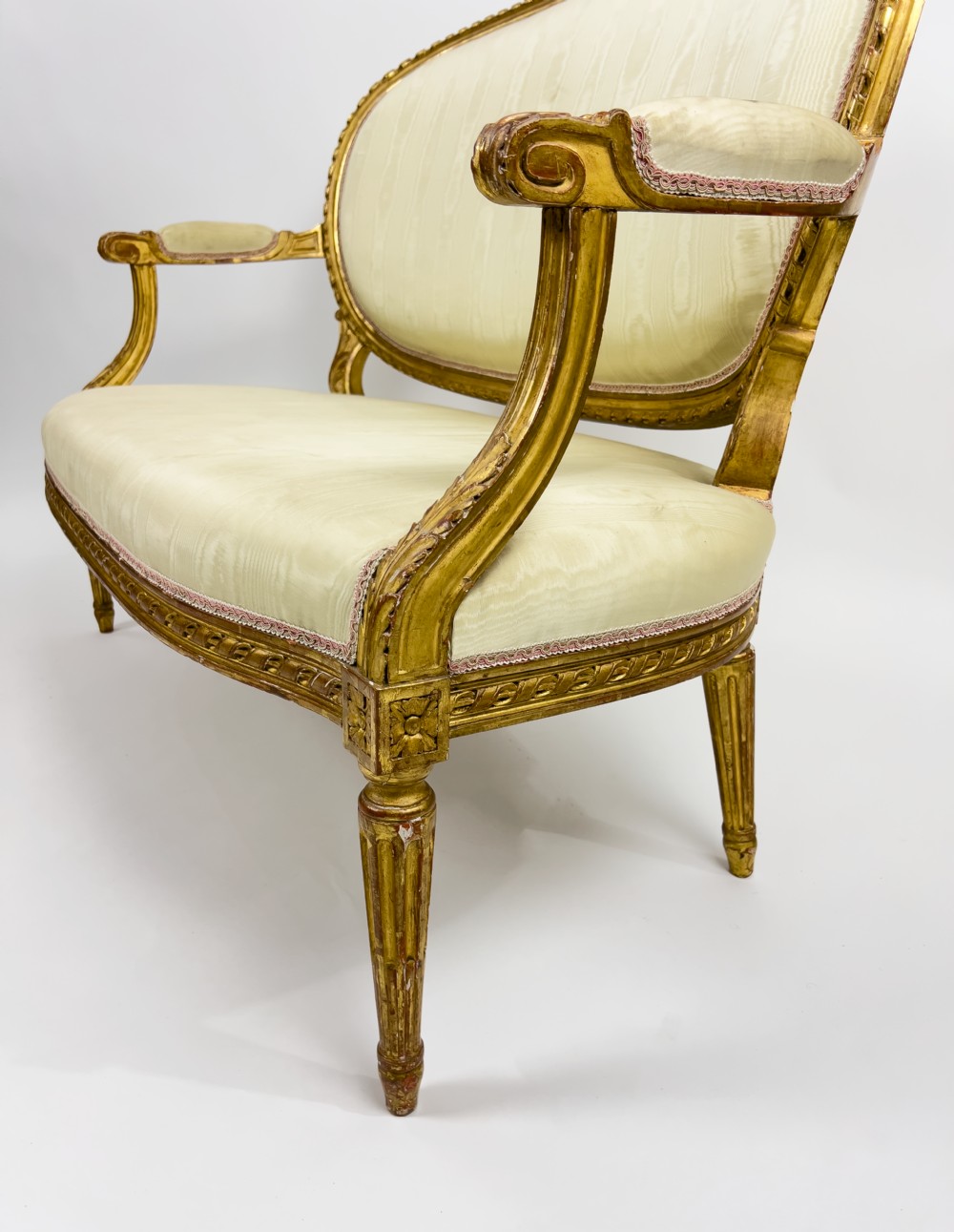 A five-piece 19th-century French Louis XVI style giltwood salon suite featuring a three-seater settee and four matching fauteuil armchairs upholstered in cream fabric. View V