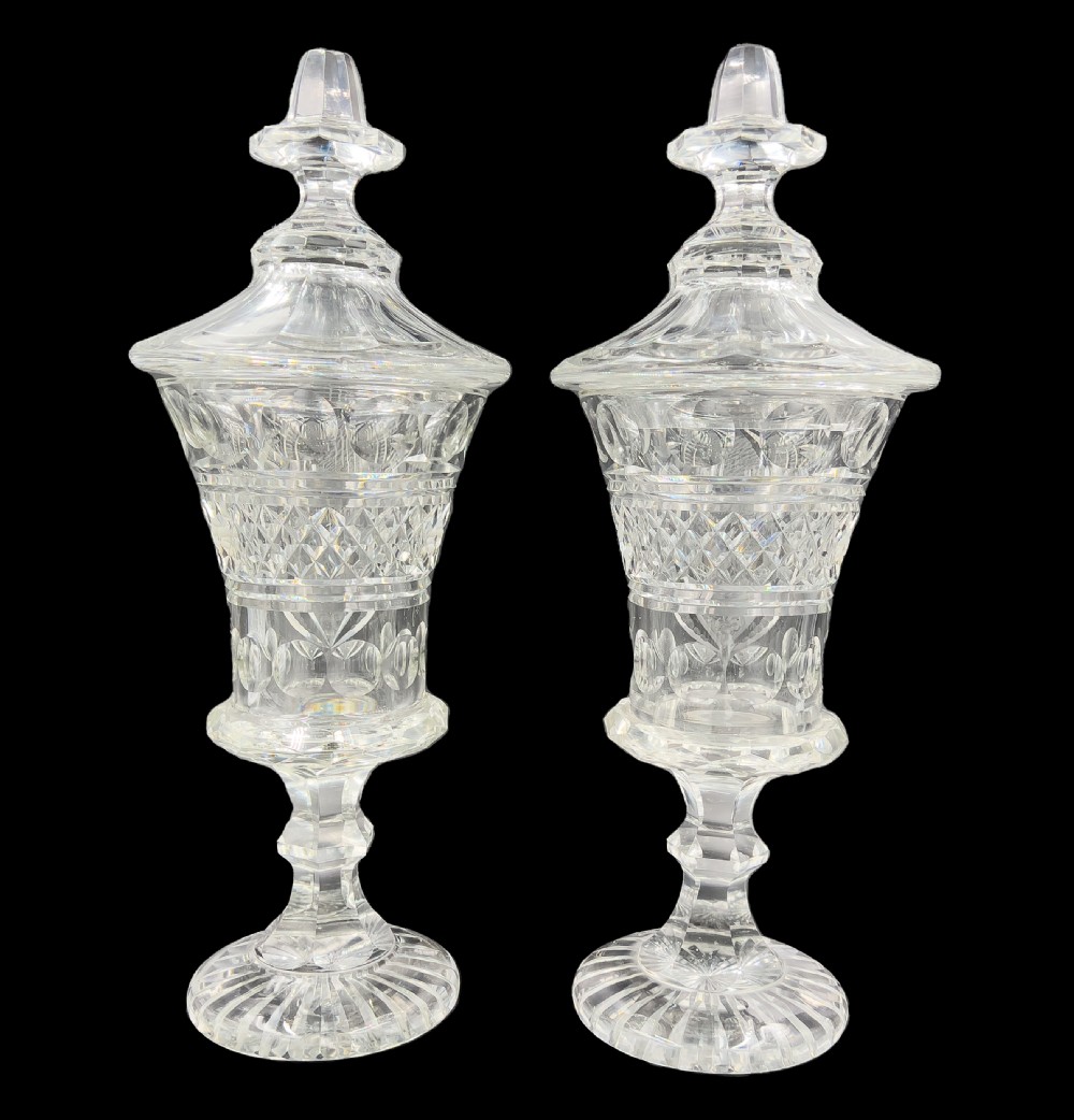 A pair of clear cut glass lidded urns featuring etched woodland motifs and faceted pedestal bases. View II