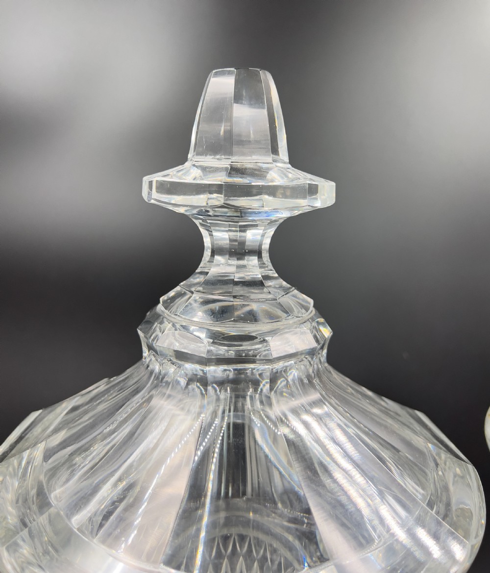 A pair of clear cut glass lidded urns featuring etched woodland motifs and faceted pedestal bases. View V