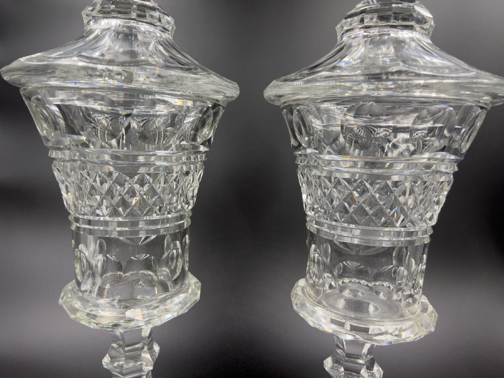 A pair of clear cut glass lidded urns featuring etched woodland motifs and faceted pedestal bases. View VII