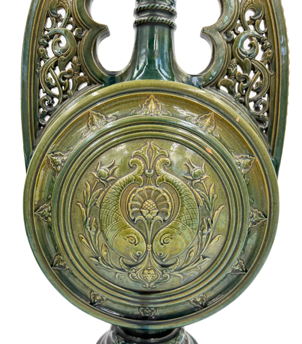 A pair of 19th-century Spanish Hispano-Moresque green glazed ceramic candlesticks featuring tall cylindrical necks, elaborate pierced scroll handles, and central circular relief medallions. View III