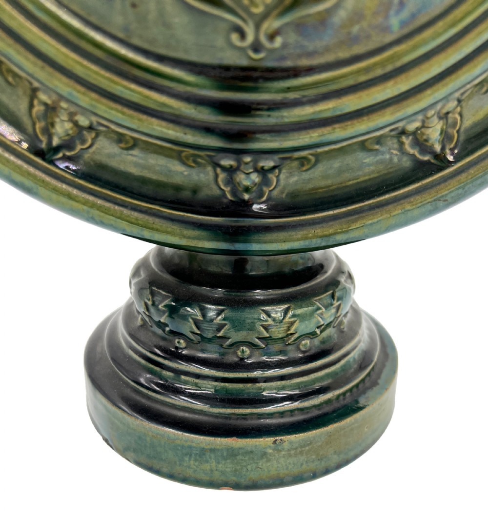 A pair of 19th-century Spanish Hispano-Moresque green glazed ceramic candlesticks featuring tall cylindrical necks, elaborate pierced scroll handles, and central circular relief medallions. View V