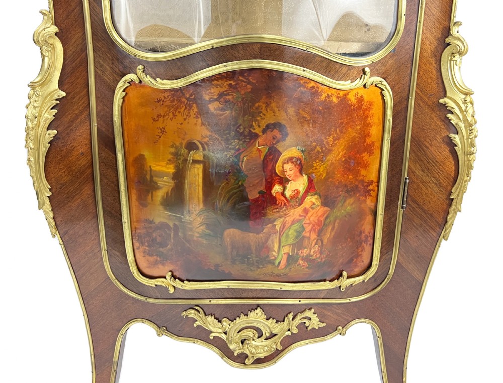 A serpentine French Louis XV style vitrine cabinet featuring gilded ormolu mounts, glazed glass door, and a hand-painted Vernis Martin lower panel depicting romantic figures. View VII