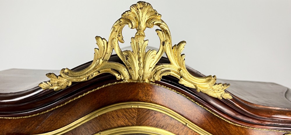 A serpentine French Louis XV style vitrine cabinet featuring gilded ormolu mounts, glazed glass door, and a hand-painted Vernis Martin lower panel depicting romantic figures. View X