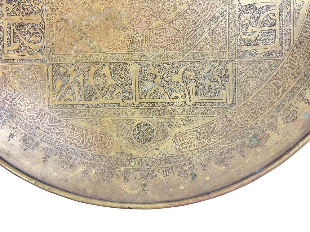 A late 19th-century round centre table featuring an intricately engraved brass top with Arabic calligraphic inscriptions resting on carved wooden barley-twist legs. View V