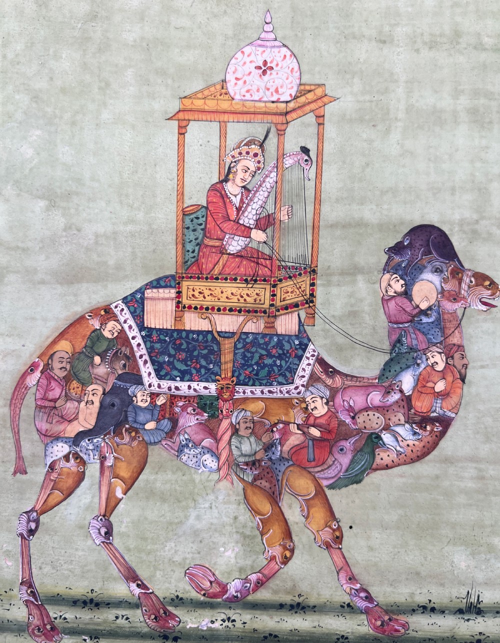 An Indian miniature painting on paper depicting a woman playing a harp within a canopy atop a composite camel, set against a pale green field and framed by a dark floral border. View IV