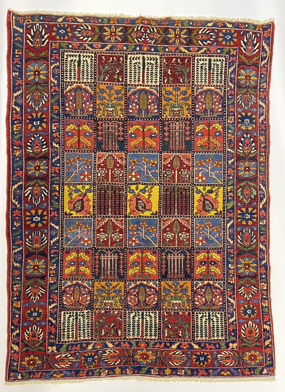 A hand-knotted Bakhtiari Persian wool rug featuring a rectangular garden compartment panel design in red, blue, green, and yellow.
