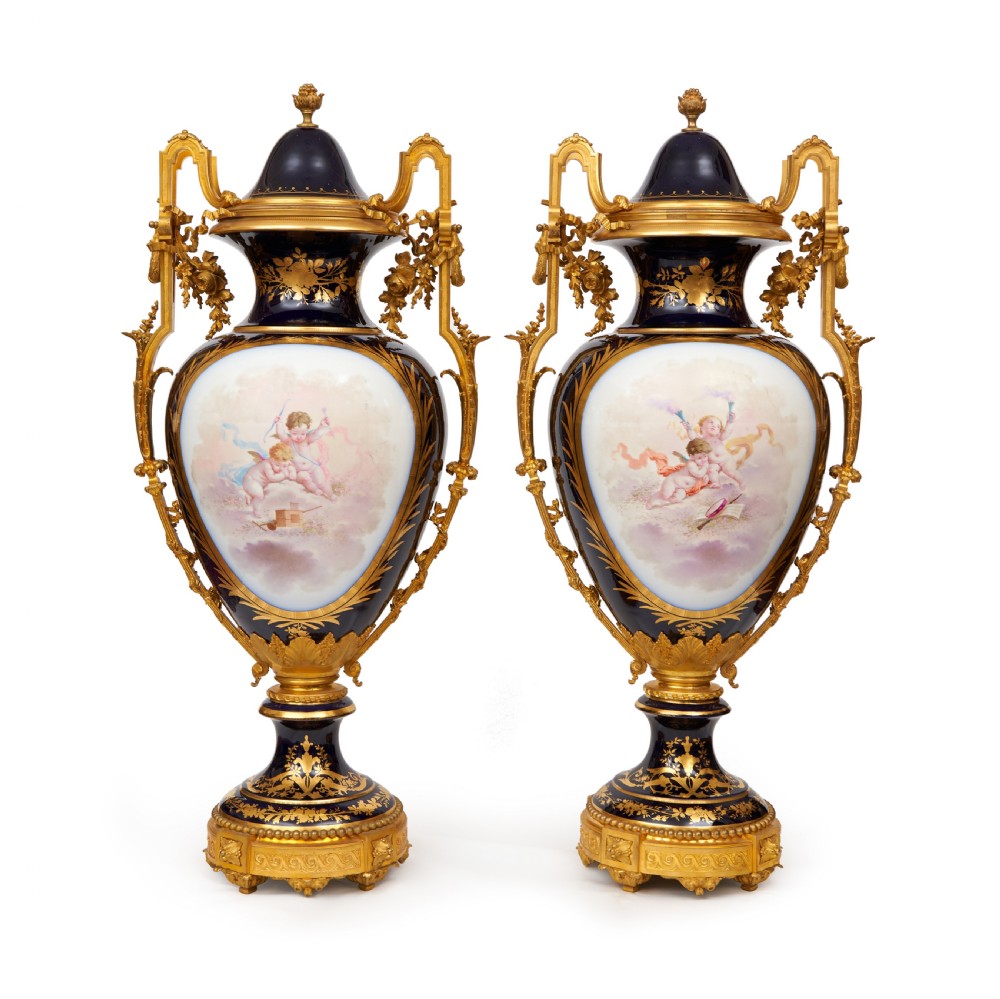 A pair of large French Sevres style cobalt blue porcelain lidded urns featuring hand-painted mythological scenes and elaborate gilded ormolu handles. View III