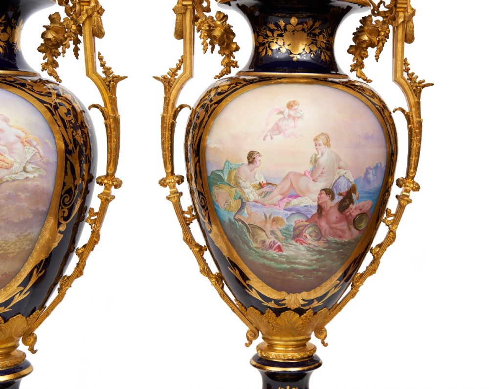 A pair of large French Sevres style cobalt blue porcelain lidded urns featuring hand-painted mythological scenes and elaborate gilded ormolu handles. View V