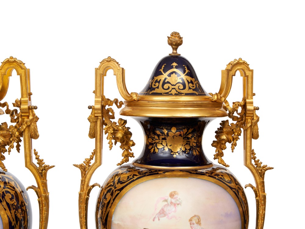 A pair of large French Sevres style cobalt blue porcelain lidded urns featuring hand-painted mythological scenes and elaborate gilded ormolu handles. View VI