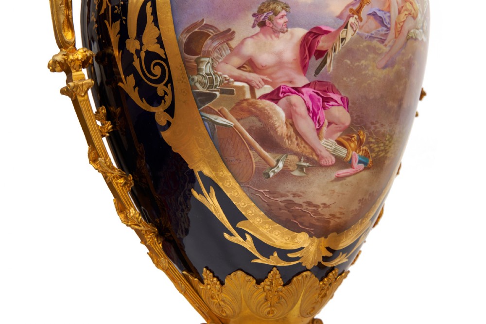 A pair of large French Sevres style cobalt blue porcelain lidded urns featuring hand-painted mythological scenes and elaborate gilded ormolu handles. View XII