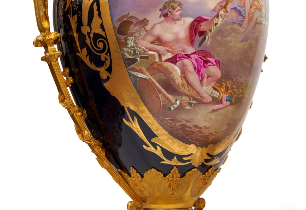 A pair of large French Sevres style cobalt blue porcelain lidded urns featuring hand-painted mythological scenes and elaborate gilded ormolu handles. View XIII