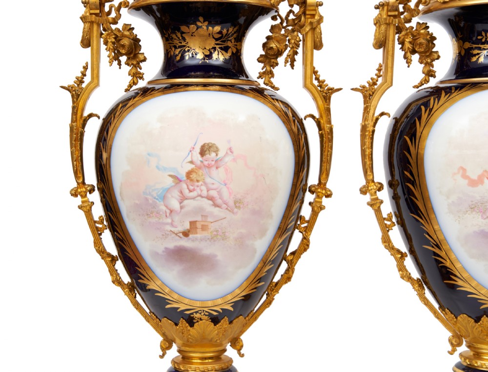 A pair of large French Sevres style cobalt blue porcelain lidded urns featuring hand-painted mythological scenes and elaborate gilded ormolu handles. View XVII