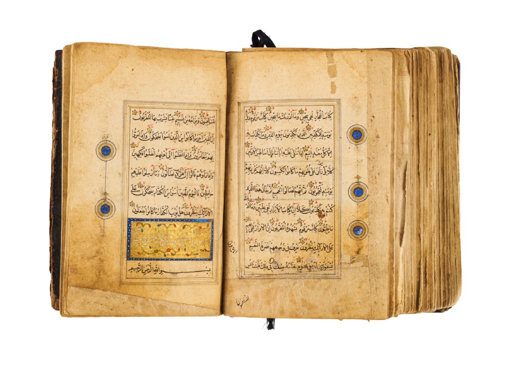 An open fifteenth-century Persian Timurid Quran manuscript featuring gold leaf and lapis lazuli blue arabesque illuminated frontispiece panels with Arabic calligraphy. View X