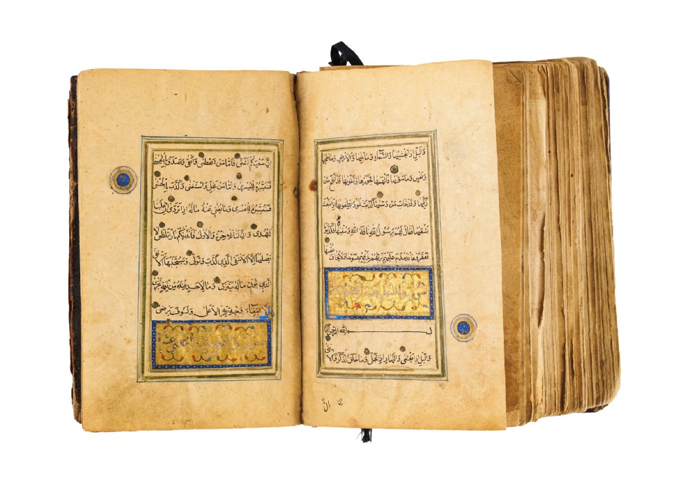 An open fifteenth-century Persian Timurid Quran manuscript featuring gold leaf and lapis lazuli blue arabesque illuminated frontispiece panels with Arabic calligraphy. View XI