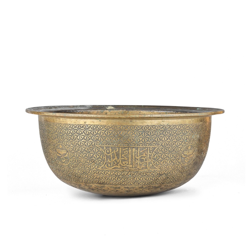 A large round brass basin featuring continuous hand-engraved Arabic calligraphic script and all-over arabesque motifs along its exterior walls. View III