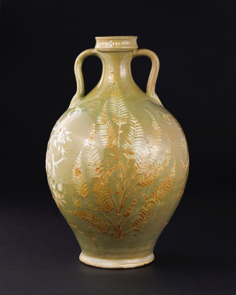 A large 17th-century Safavid pottery vase with twin handles, finished in an olive-green celadon glaze and painted with white and brown botanical foliage motifs.