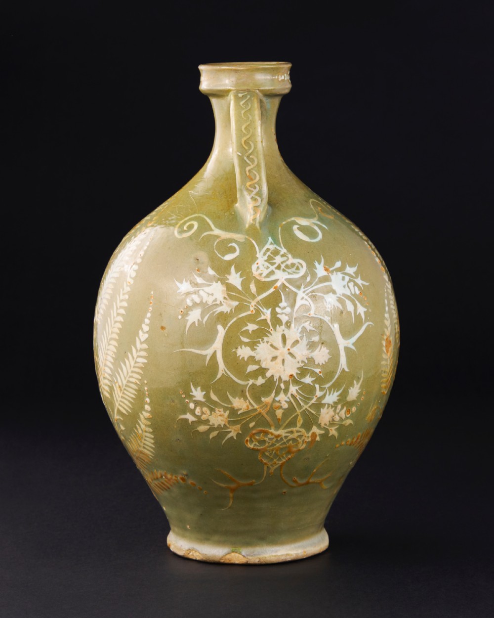 A large 17th-century Safavid pottery vase with twin handles, finished in an olive-green celadon glaze and painted with white and brown botanical foliage motifs. View II