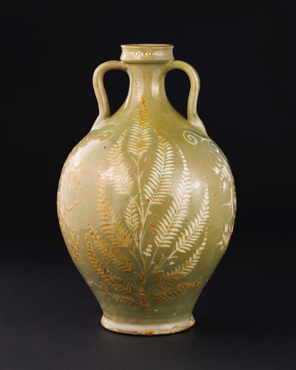 A large 17th-century Safavid pottery vase with twin handles, finished in an olive-green celadon glaze and painted with white and brown botanical foliage motifs. View III