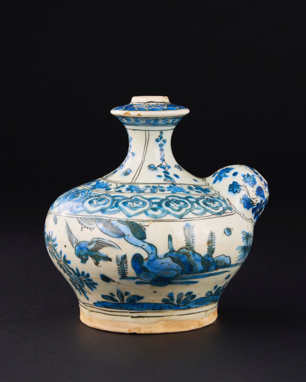 A 17th-century Safavid pottery kendi with blue underglaze painting depicting birds and foliage on a cream background.