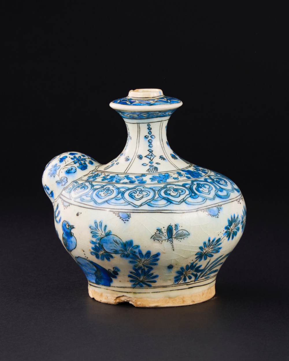 A 17th-century Safavid pottery kendi with blue underglaze painting depicting birds and foliage on a cream background. View II