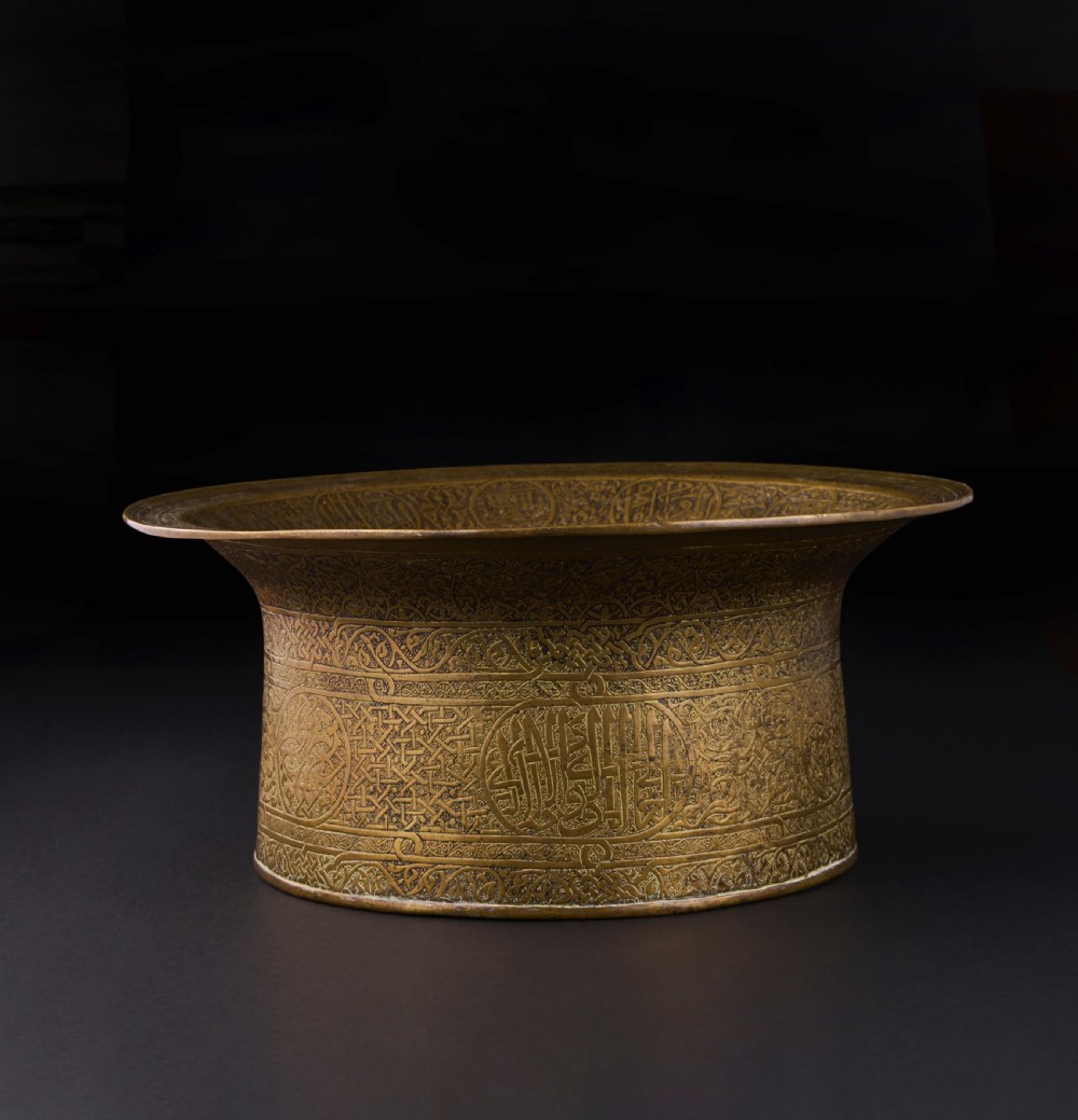 A 16th-century Mamluk brass basin featuring a wide flared rim, intricate hand-engraved Arabic calligraphy, arabesques, and geometric patterns. View III
