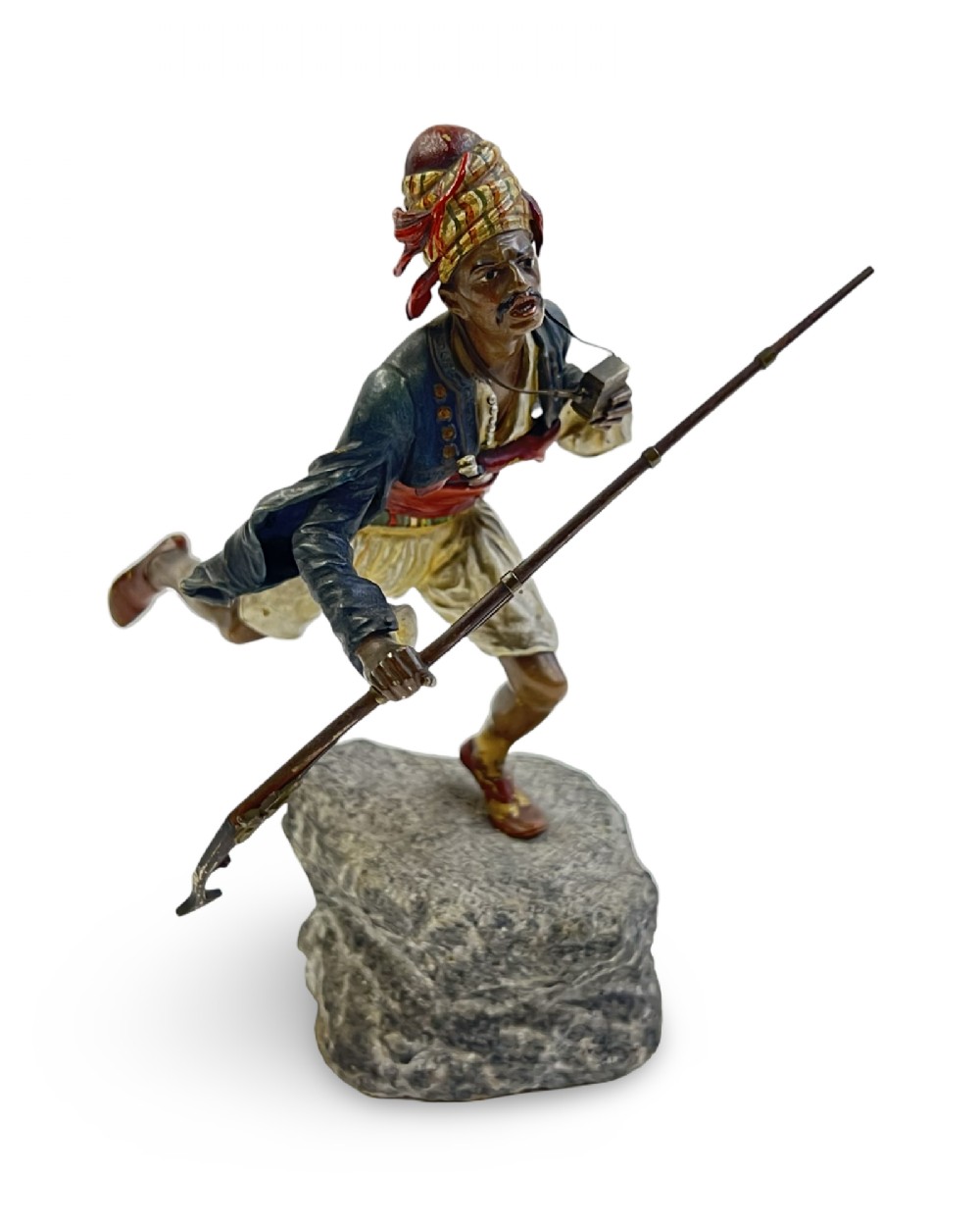 A cold-painted bronze figure depicting a Moorish warrior in motion on a faux rock base, holding a long rifle.